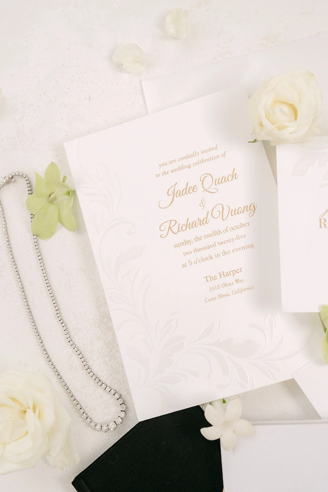 Jadee and Richard's invitation styled with a pearl necklace and white flowers