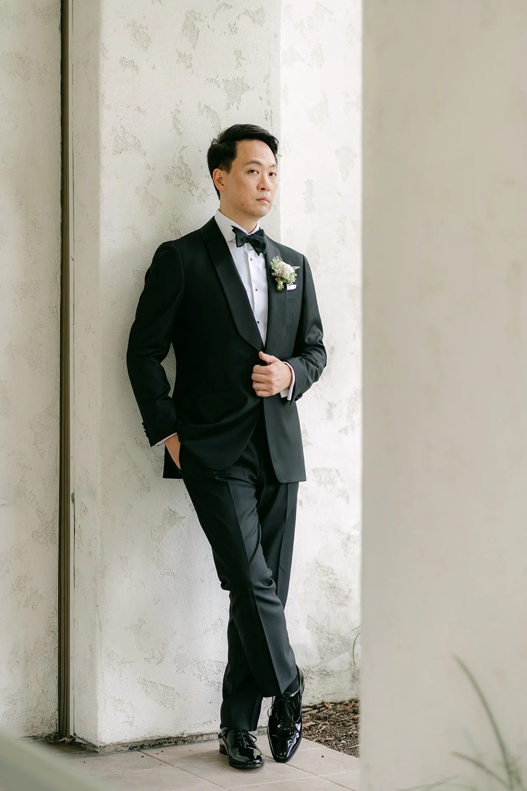 William leaning against a white column in his tuxedo
