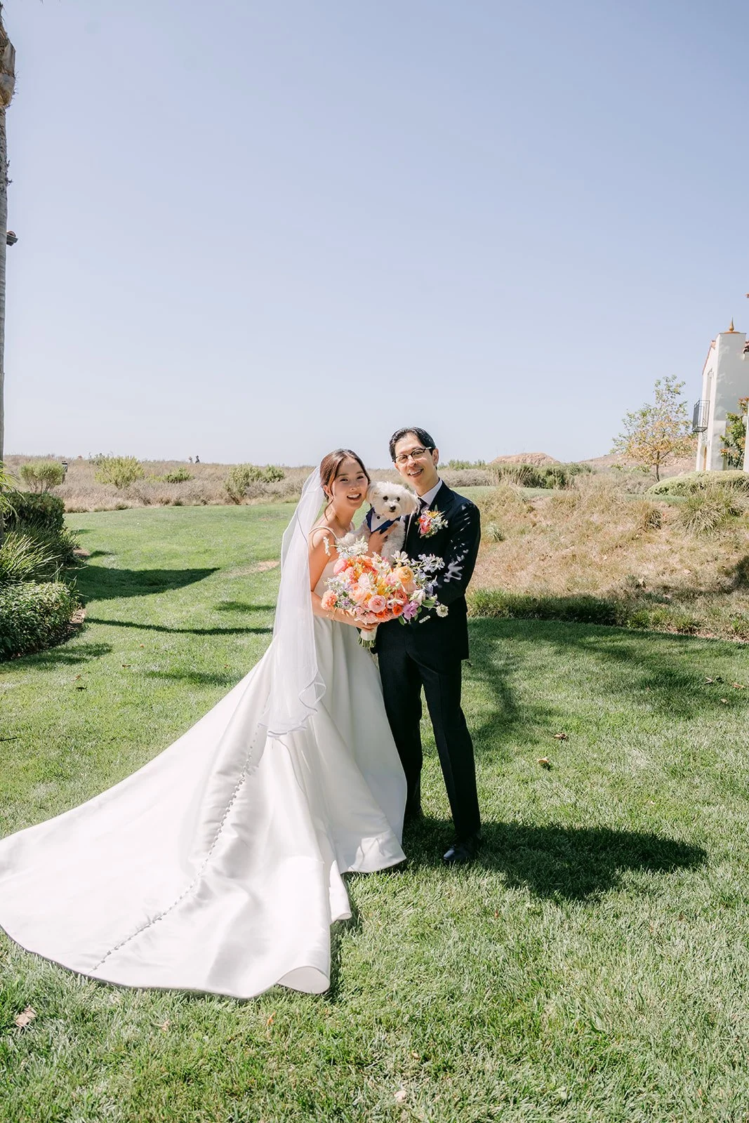 A wide coastal portrait with the gown's train spread on the grass