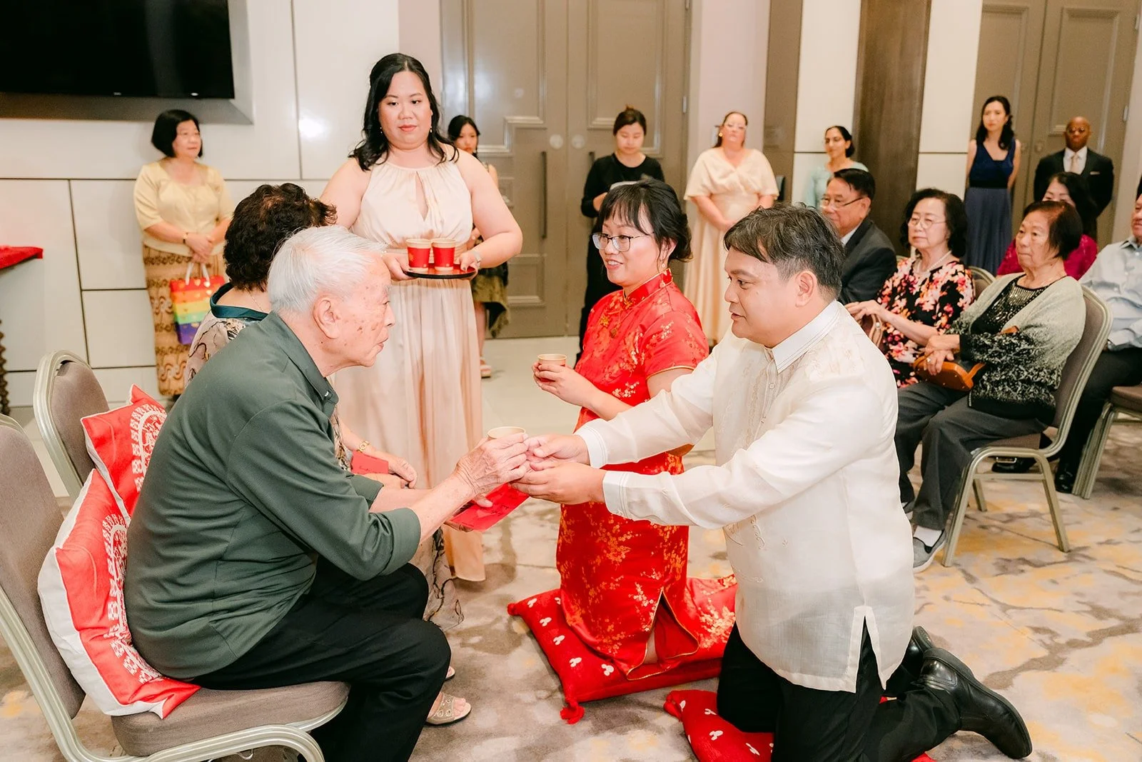James kneeling with a cup of tea while Stella offers tea beside him during the tea ceremony