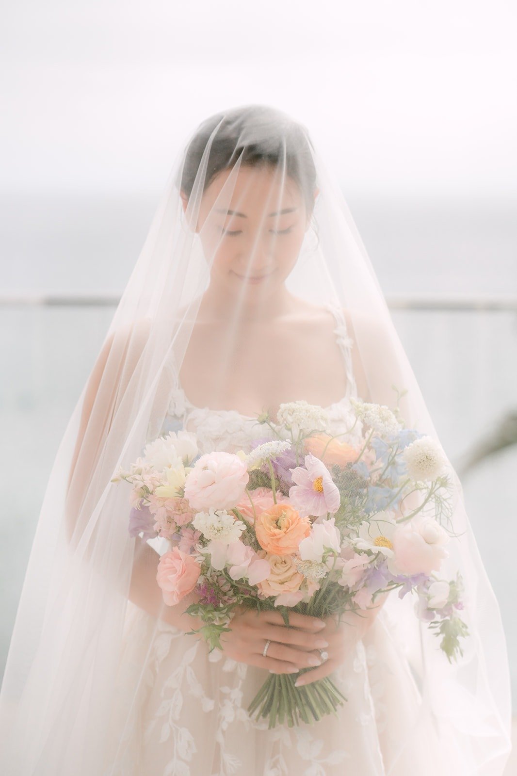 Kylie under her veil looking down at her bouquet
