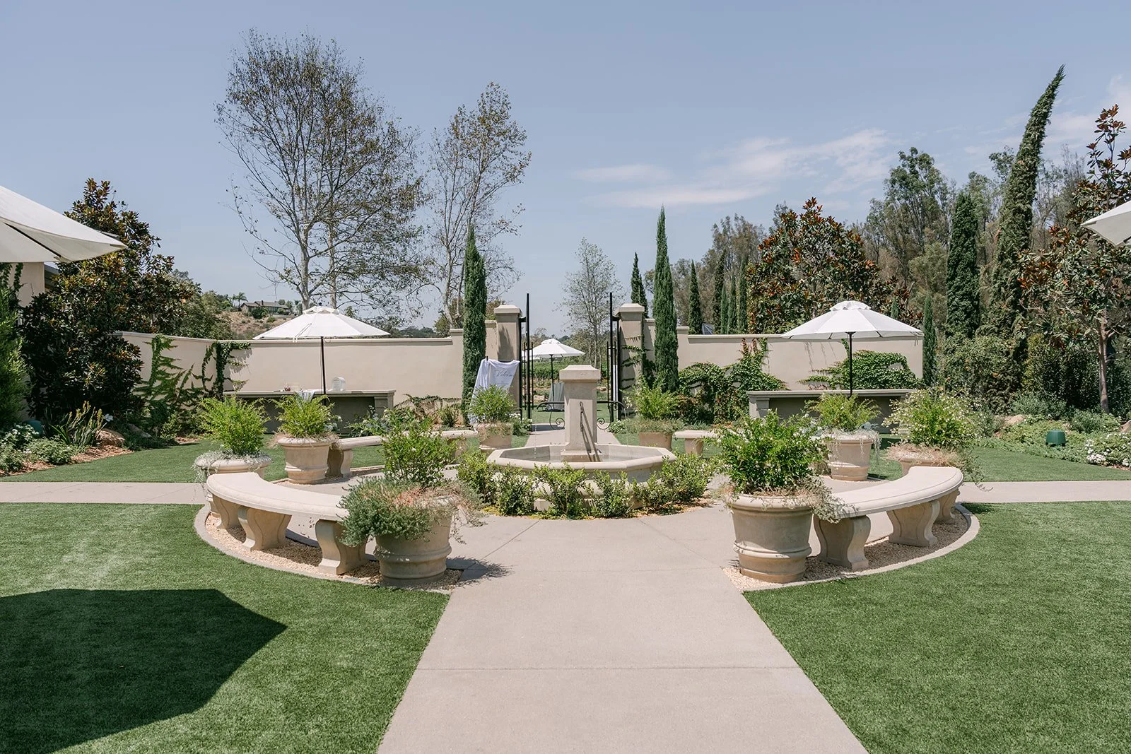 Fountain courtyard with manicured lawns and white umbrellas at Monte Bella