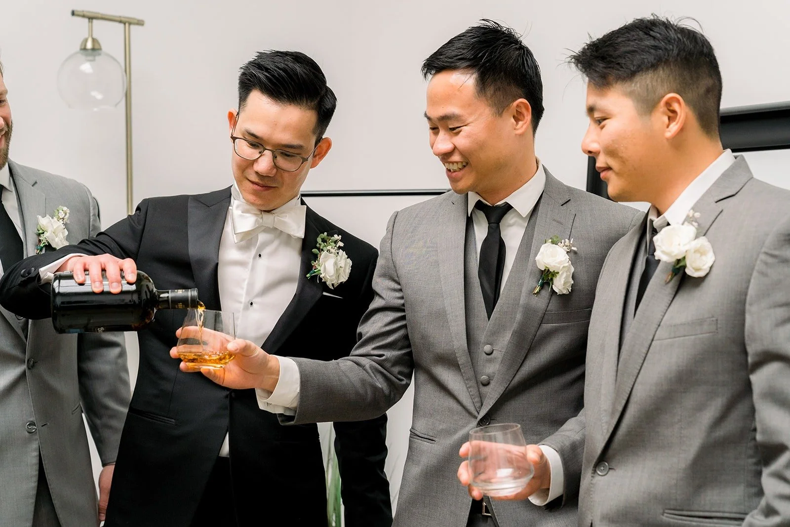 Groomsmen in grey suits pour a toast with Alex