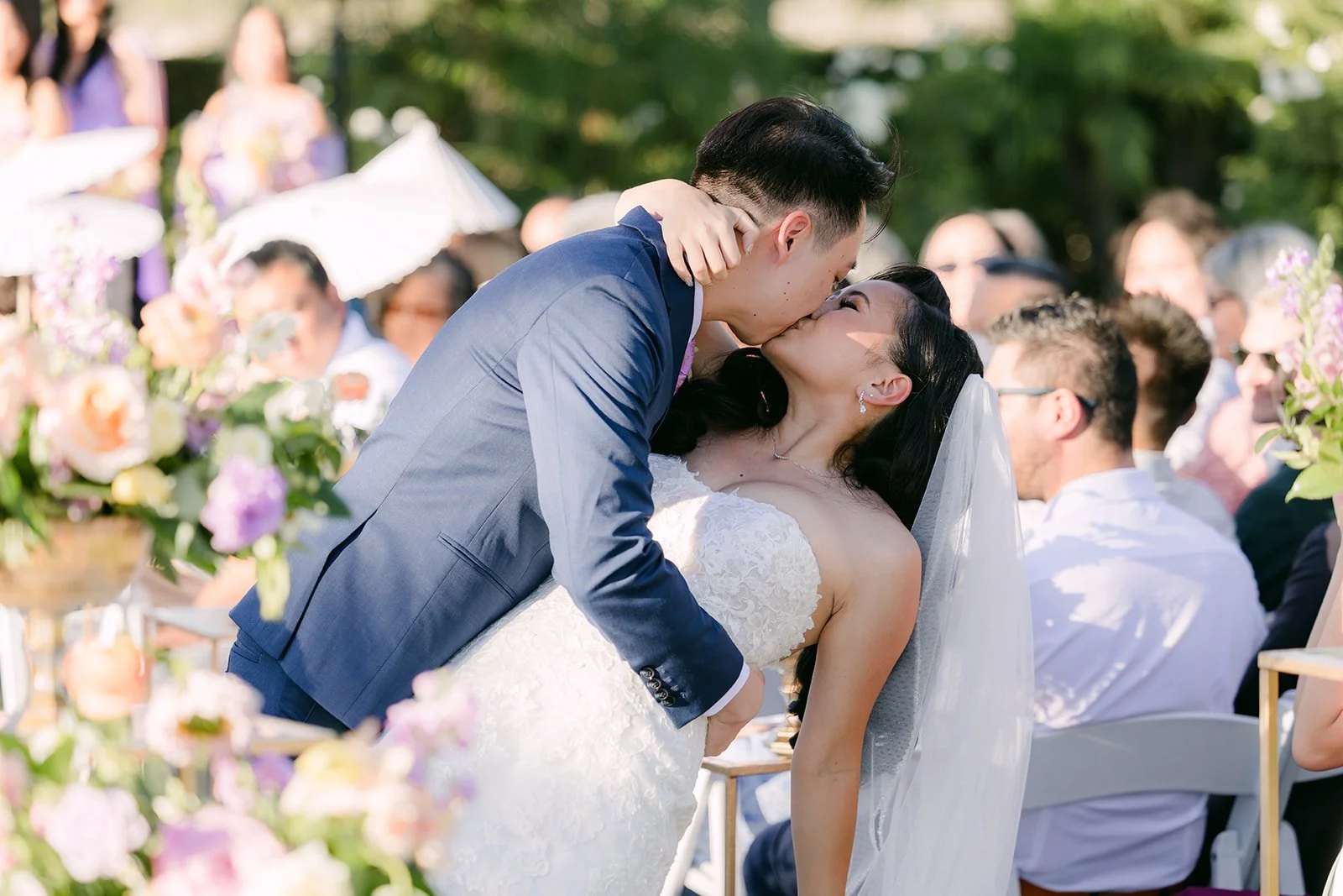 Vannie and Elijah kissing in the aisle among their guests.