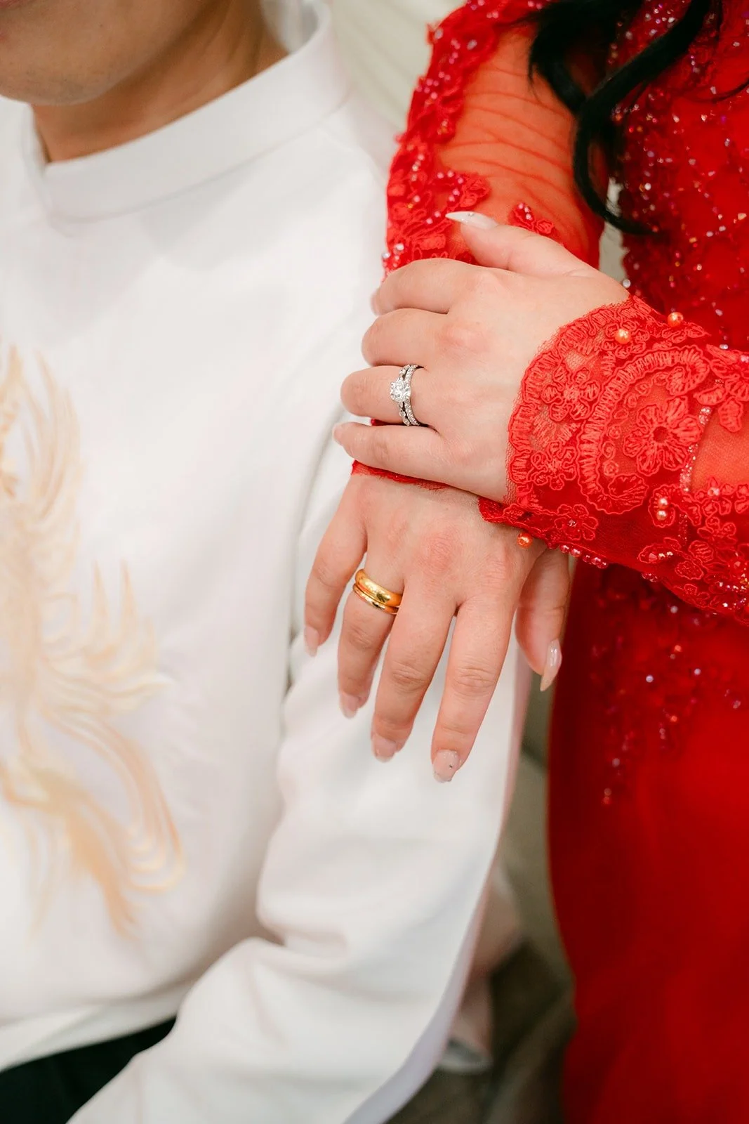 Jennifer's hand with her new wedding ring rests on Kevin's white ao dai, photographed by One and Only Production