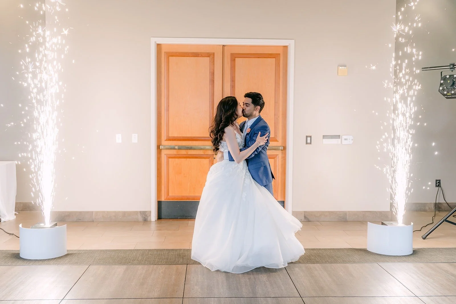 Natalie and Mark kissing between cold sparkler fountains at their grand entrance