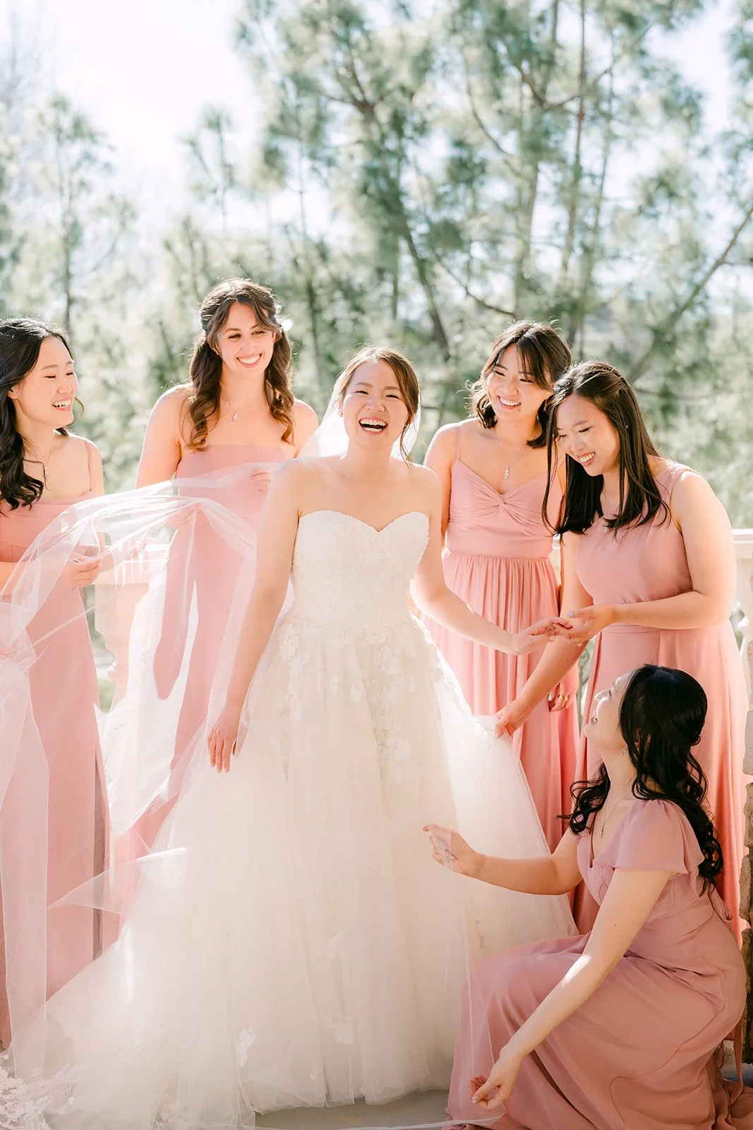 Bridesmaids fluffing the bride's veil and gown