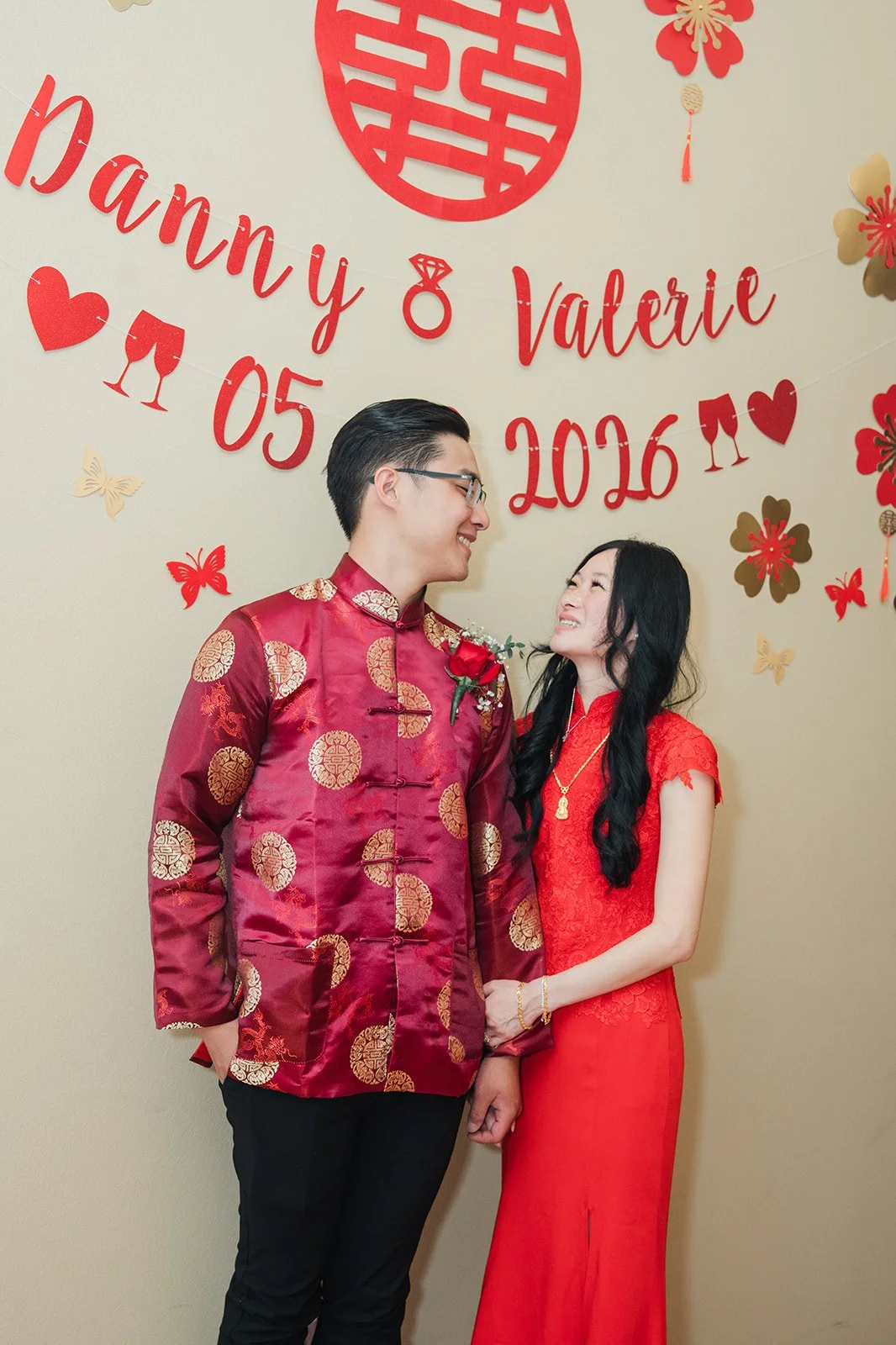 Valerie and Danny smiling in front of the backdrop.
