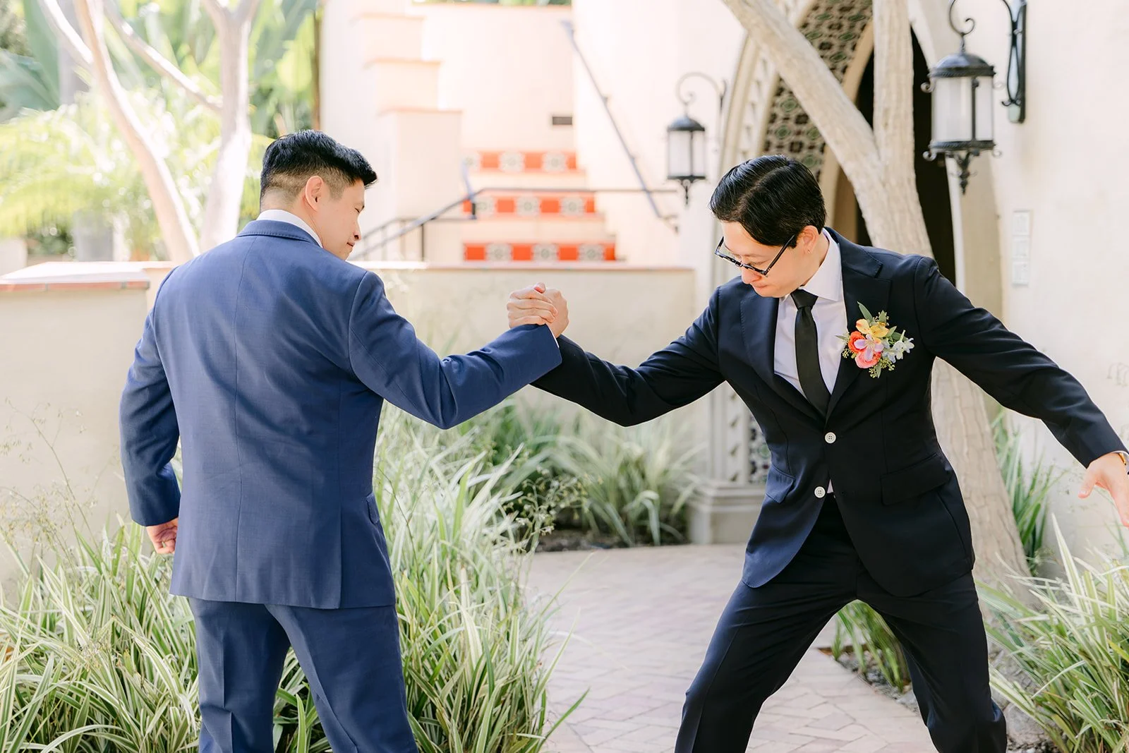 Leroy fist-bumping a groomsman in the courtyard