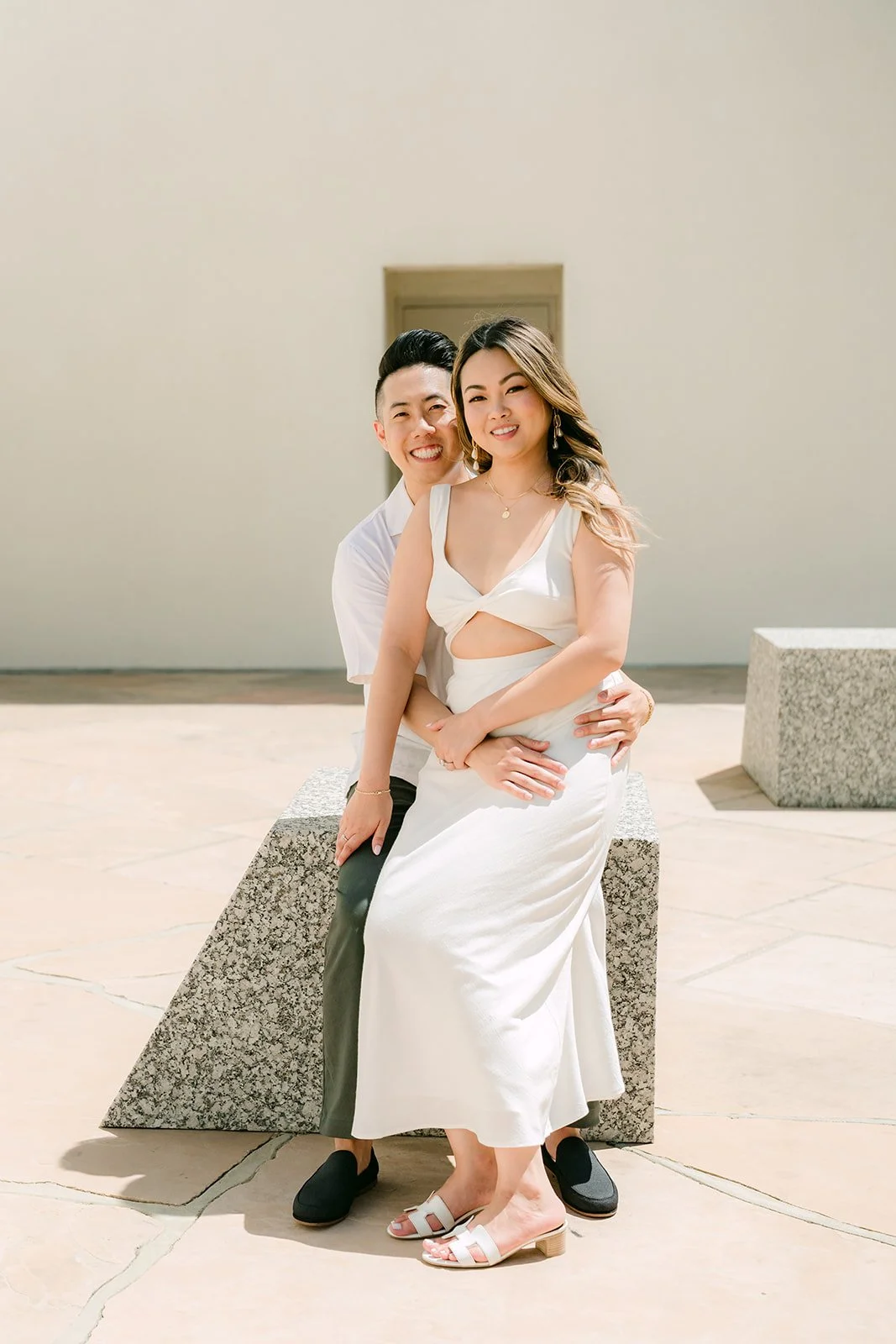 Stephanie sits on Alan's lap on a granite block.