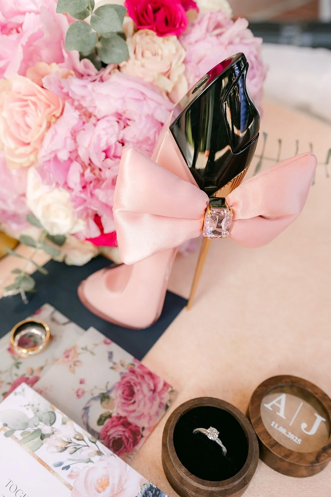 Wedding rings in wooden ring boxes beside a pink ribbon and peonies