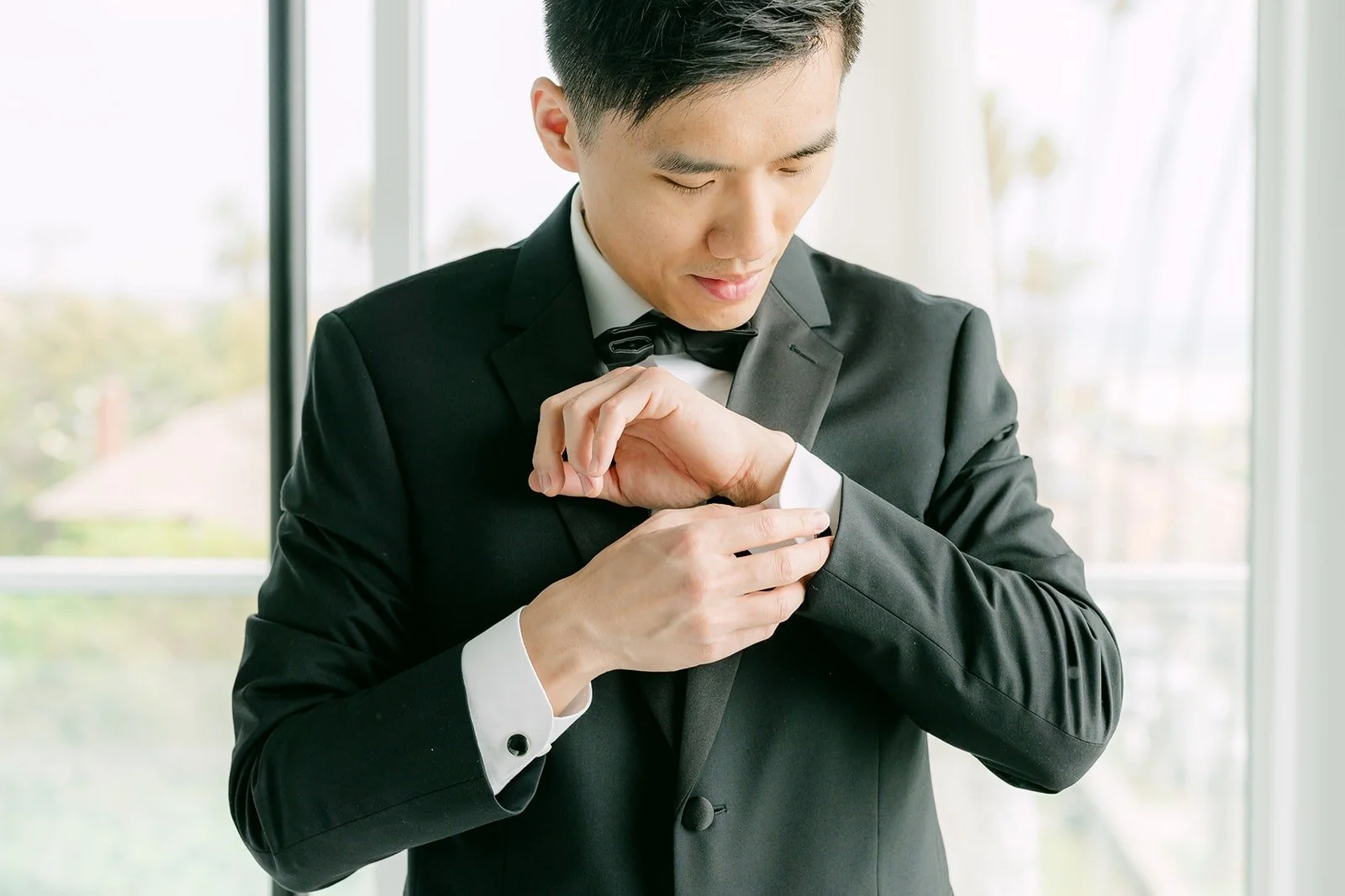 Eli fastening his cuff in his tuxedo and bow tie
