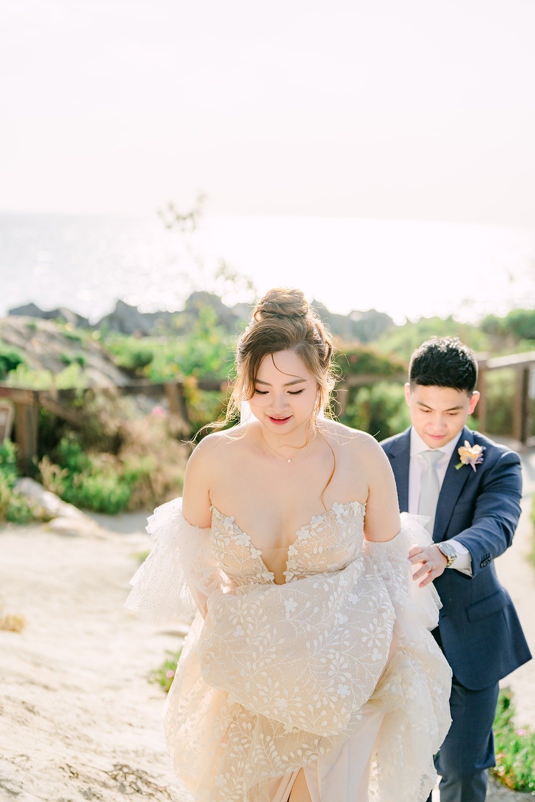 Joanna gathering her gown on the sand as Jerrick looks on