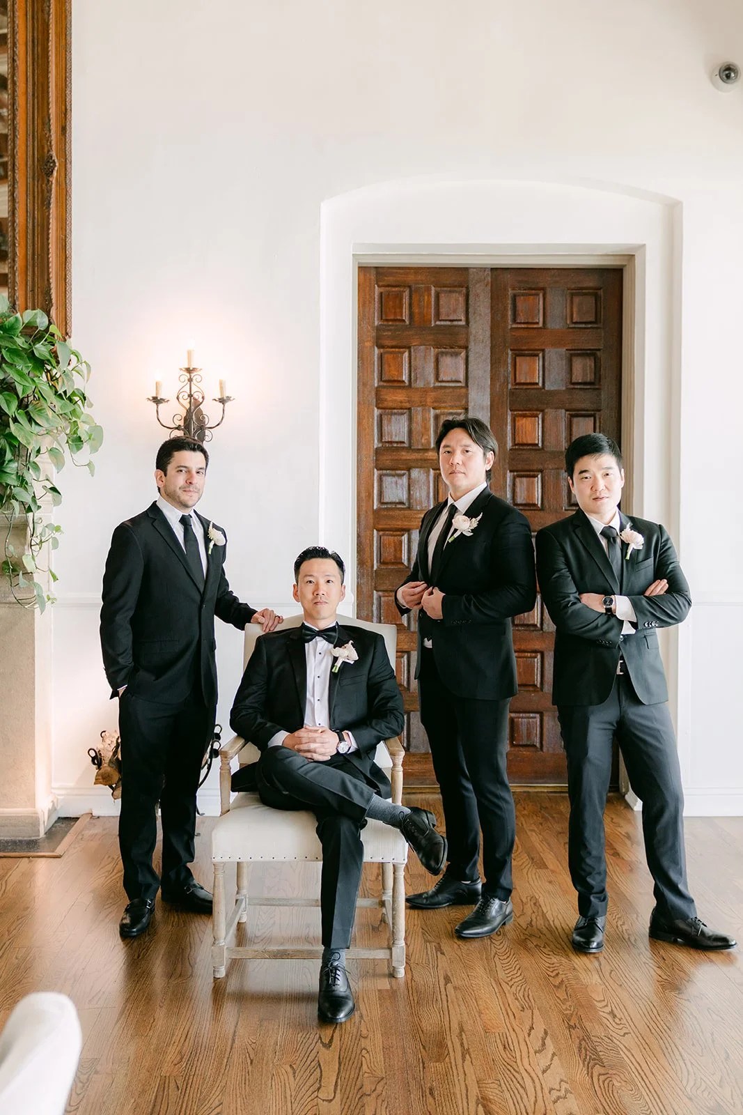 Groom seated with his groomsmen in front of carved wooden doors