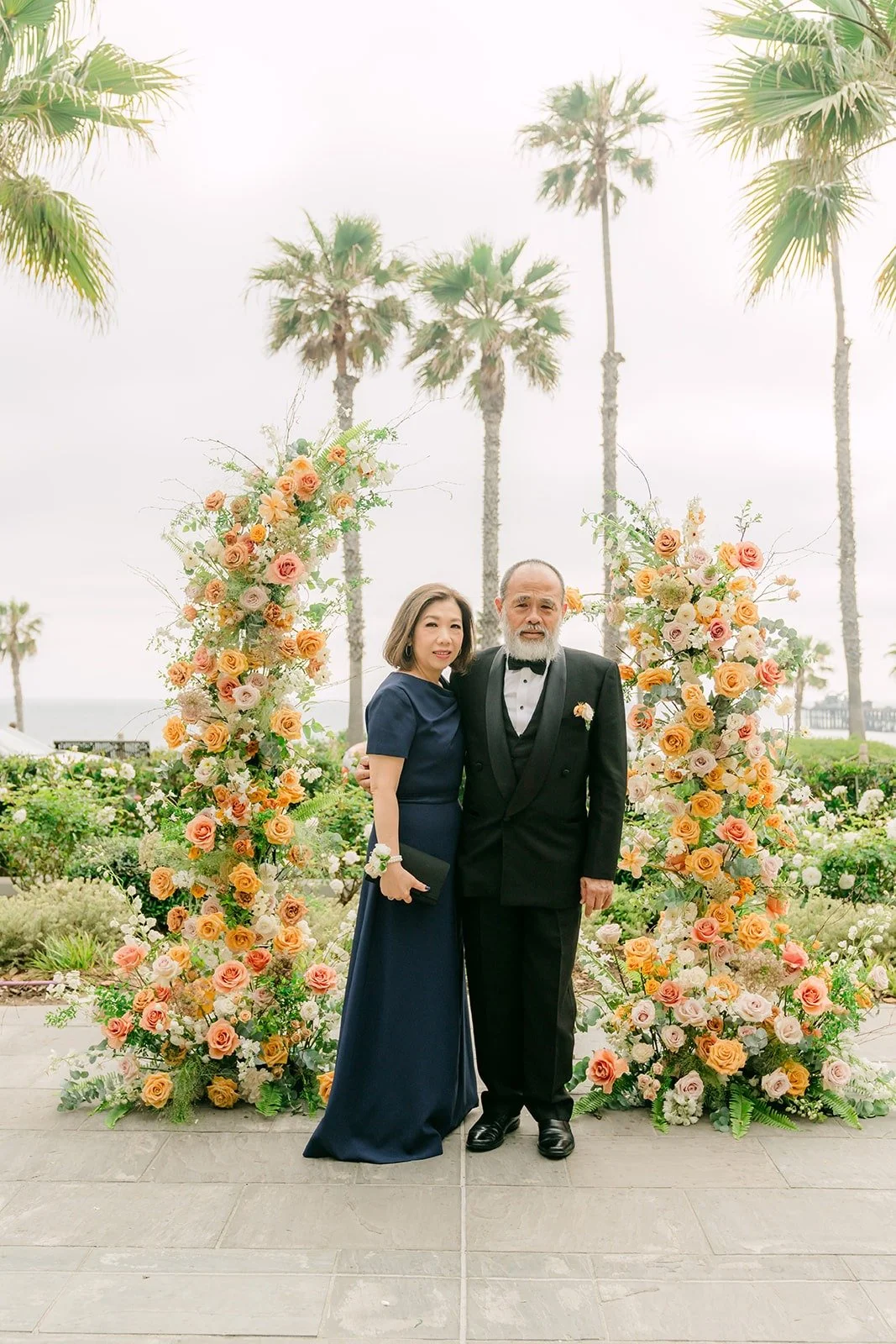 Angela and Eli with two family members in front of the floral arch