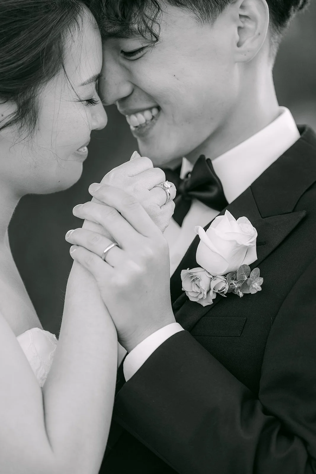 Black and white close-up of the couple holding hands forehead to forehead