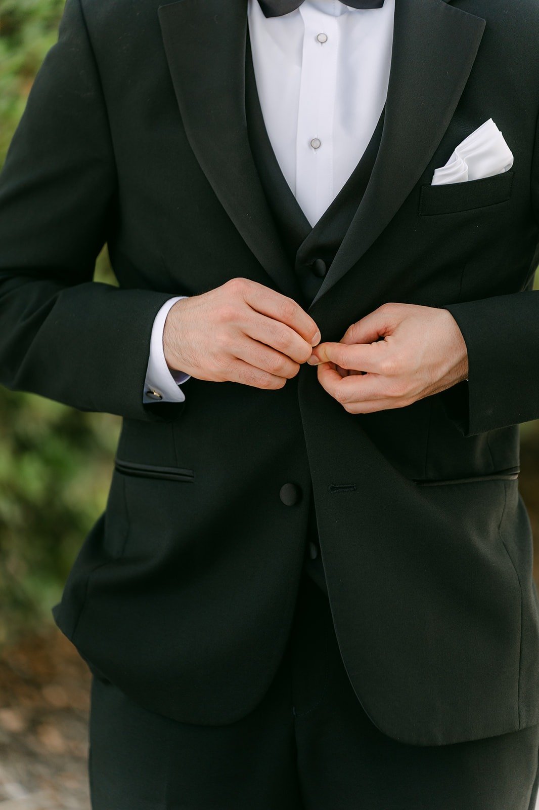 Kevin buttoning the jacket of his black tuxedo