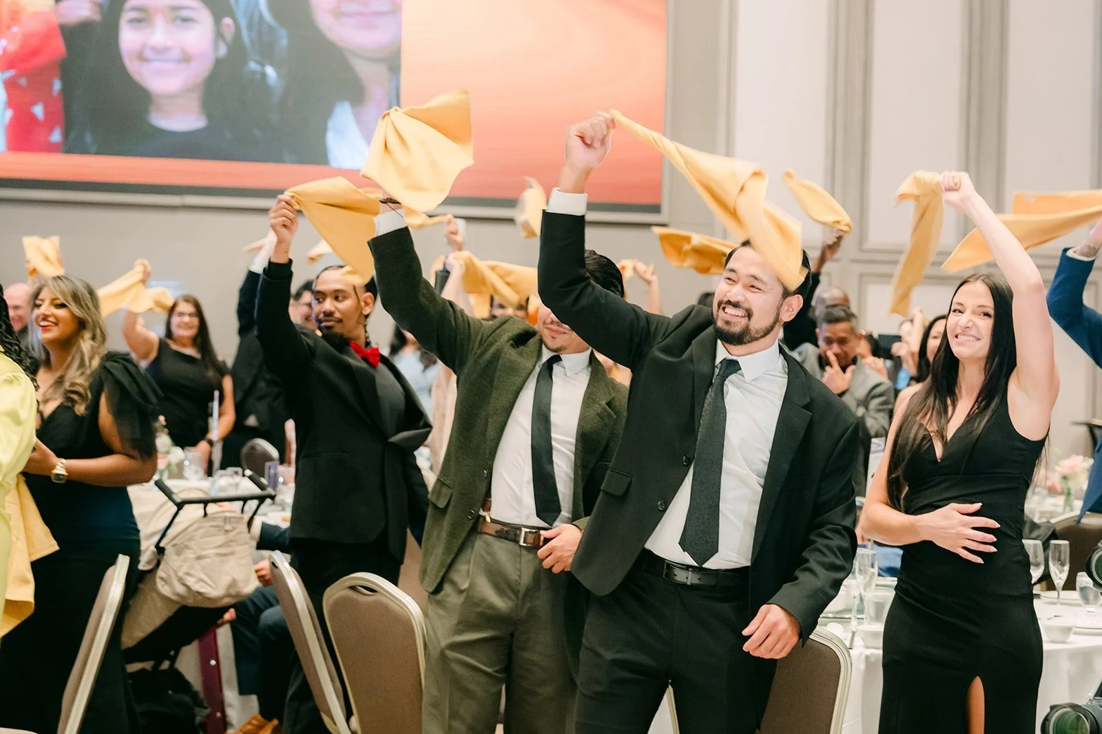 Guests waving napkins over their heads as the wedding party enters