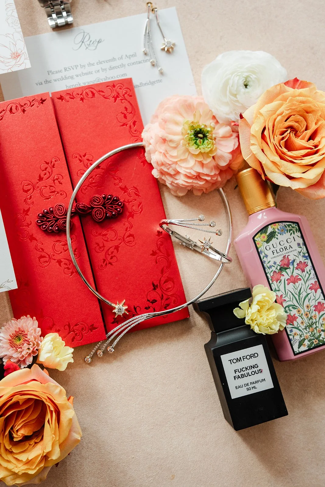 A red envelope and floral accessories laid out with Bridgette's details.