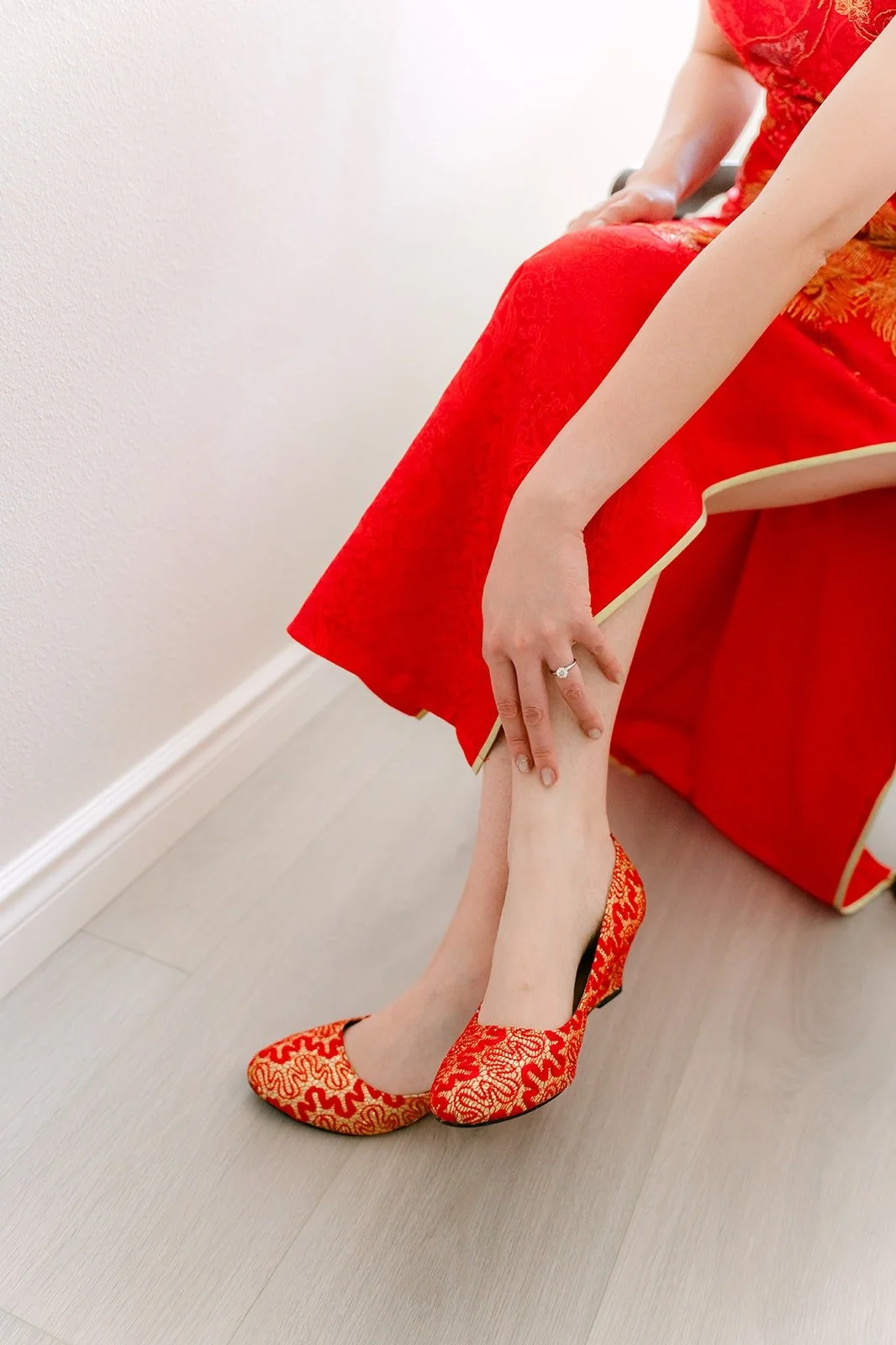 Eunice's red and gold beaded shoes under the hem of her red qipao