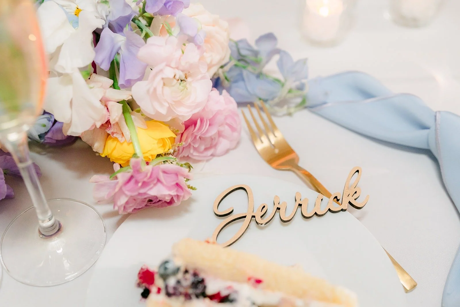 A gold name card for Jerrick tucked among pastel flowers, photographed by One and Only Production