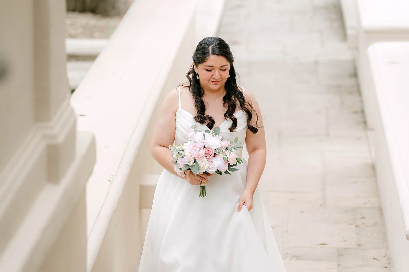 Saira coming down the steps holding her blush rose bouquet