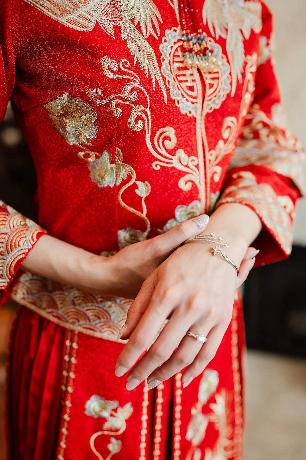 Detail of gold bangles and embroidered sleeves on a red qun kwa.