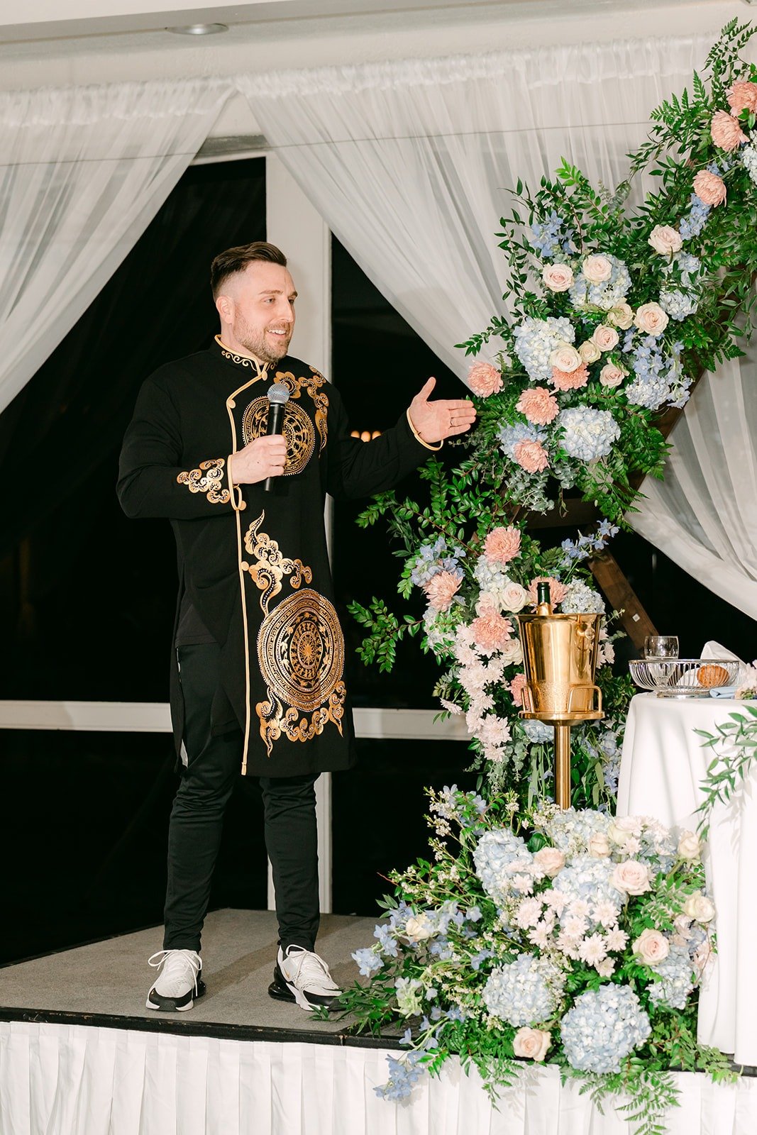 A guest giving a speech beside the floral arch