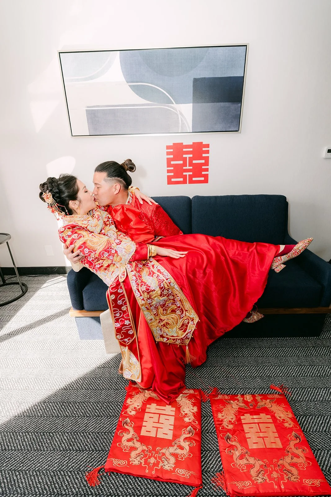 A bride leaning in to kiss the groom on a red runner after the tea ceremony.