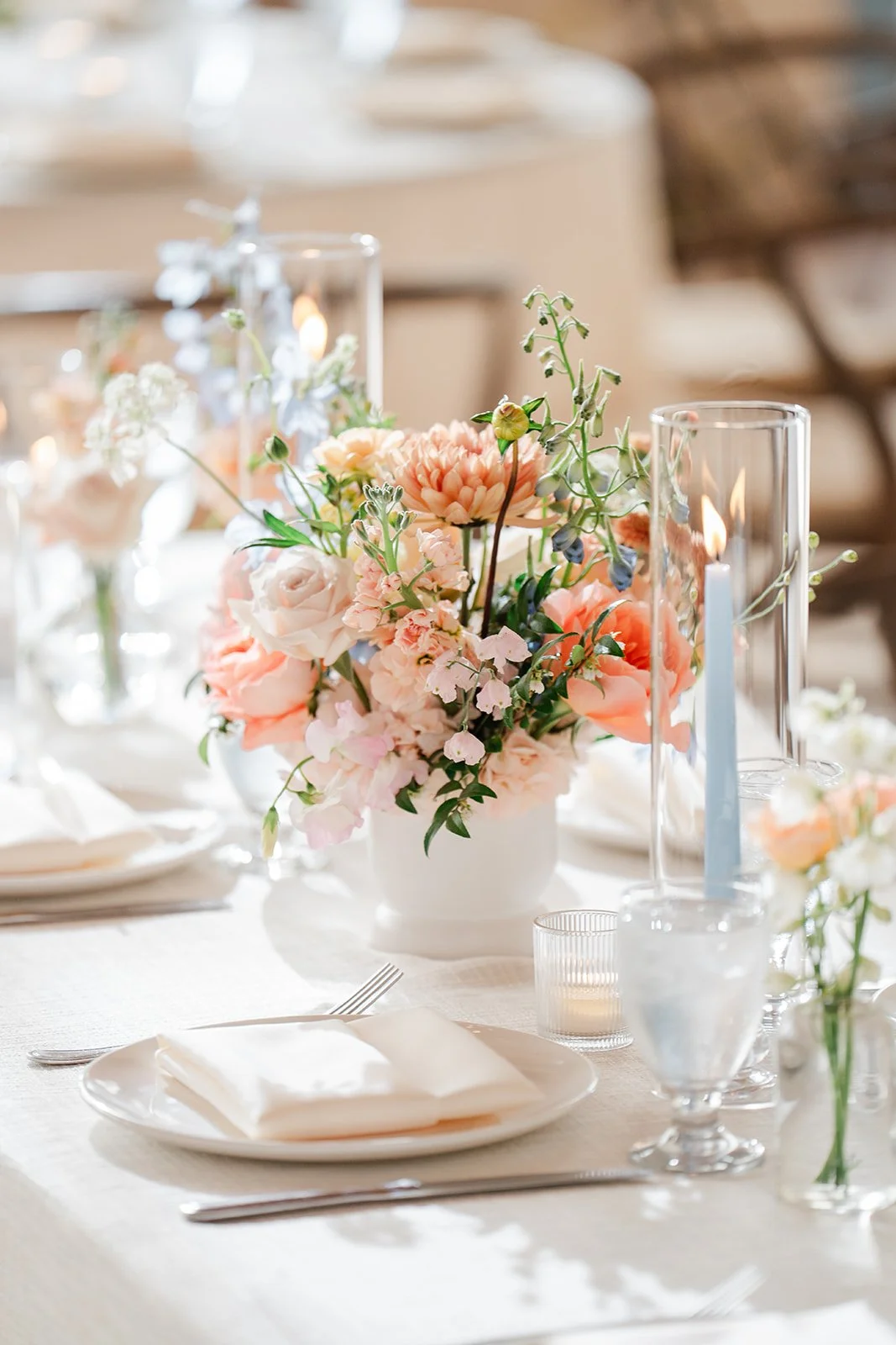 Centerpiece of pastel flowers with a blue taper candle