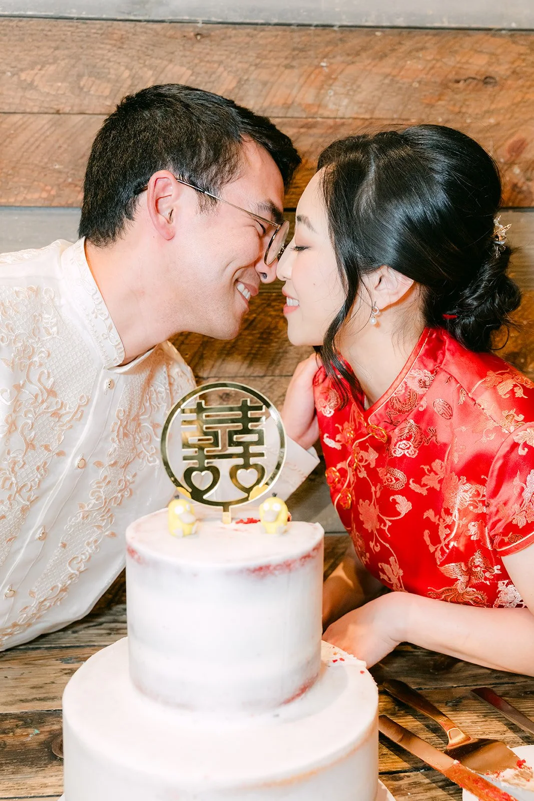 Yishan and Jonathan sharing a bite of cake, bride in her red qipao