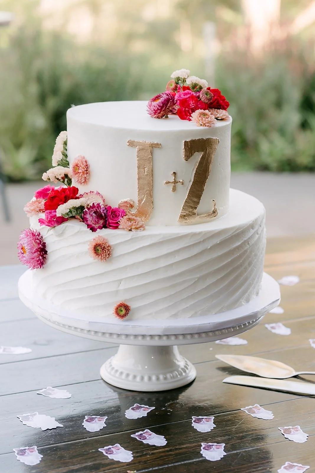 The white wedding cake with a gold J and Z topper and red flowers