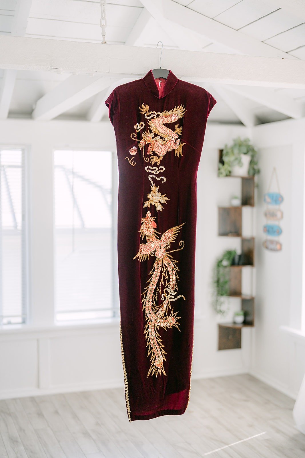 Jadee's burgundy qipao with gold embroidery hanging in the suite