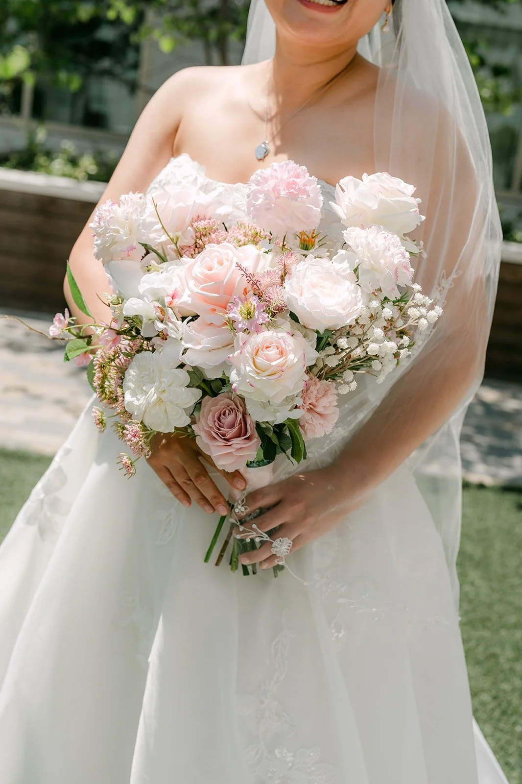 Close detail of Stella holding her bouquet of blush and white flowers