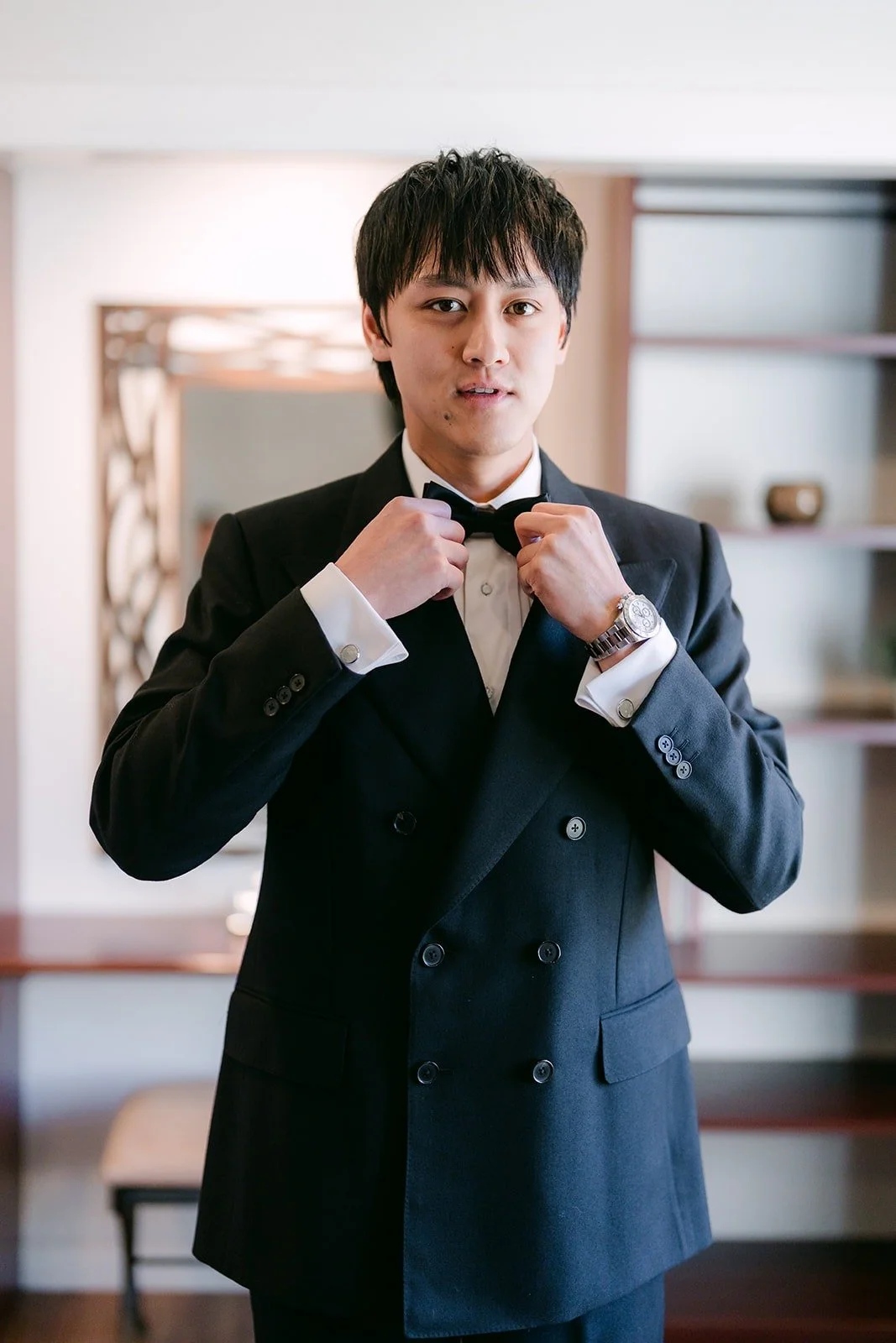 Job straightening his bow tie in a double breasted tuxedo