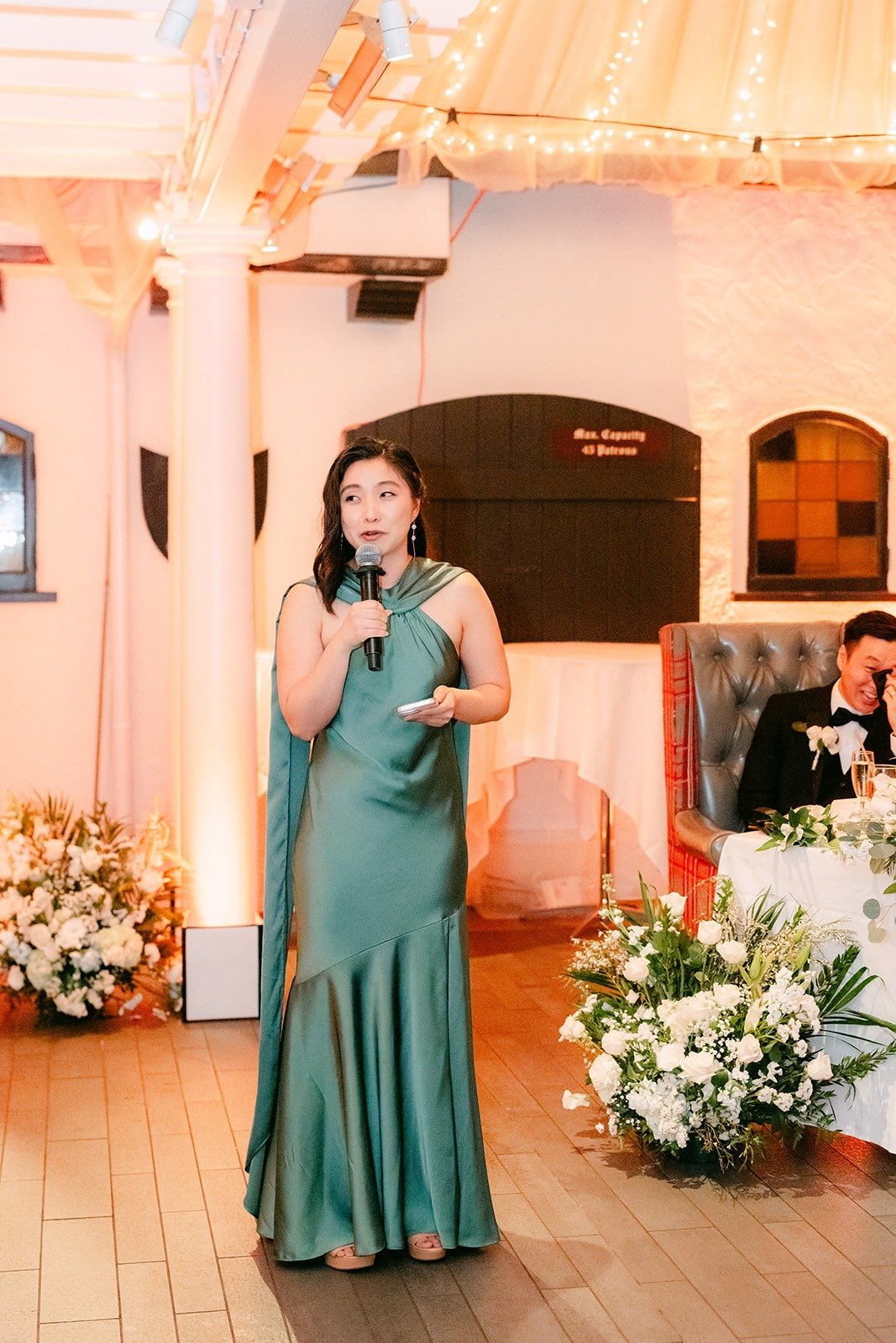 A bridesmaid giving a speech in a sage green dress