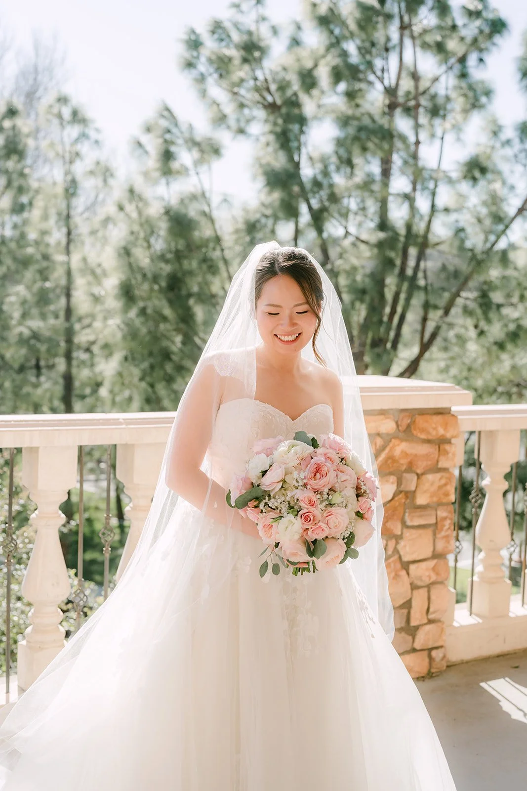 Victoria holding her blush rose bouquet on the balcony at Vellano Estate