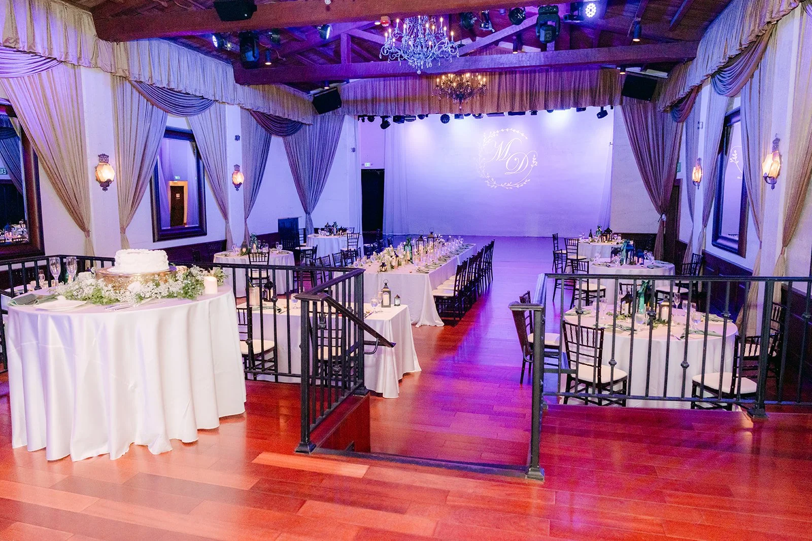 Wide view of the reception room with round tables and the stage