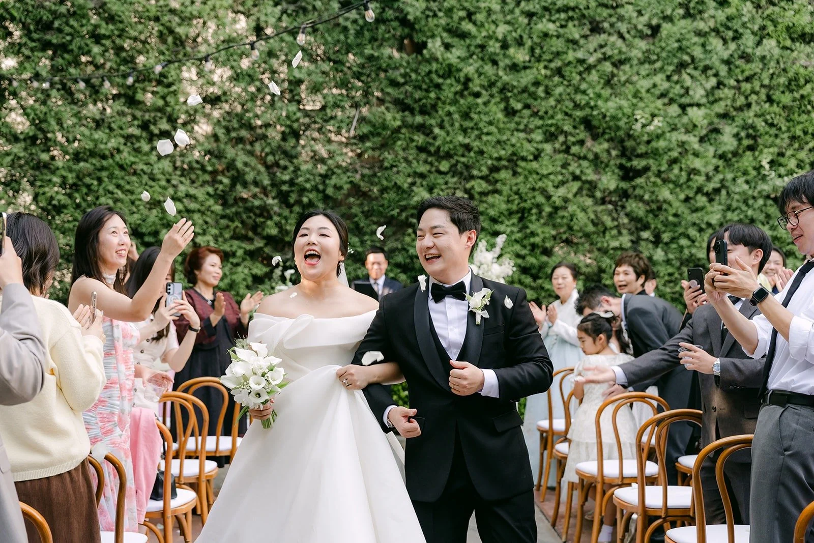 Chorok and Min Soo walking back up the aisle as married to cheers from their guests, photographed by One and Only Production