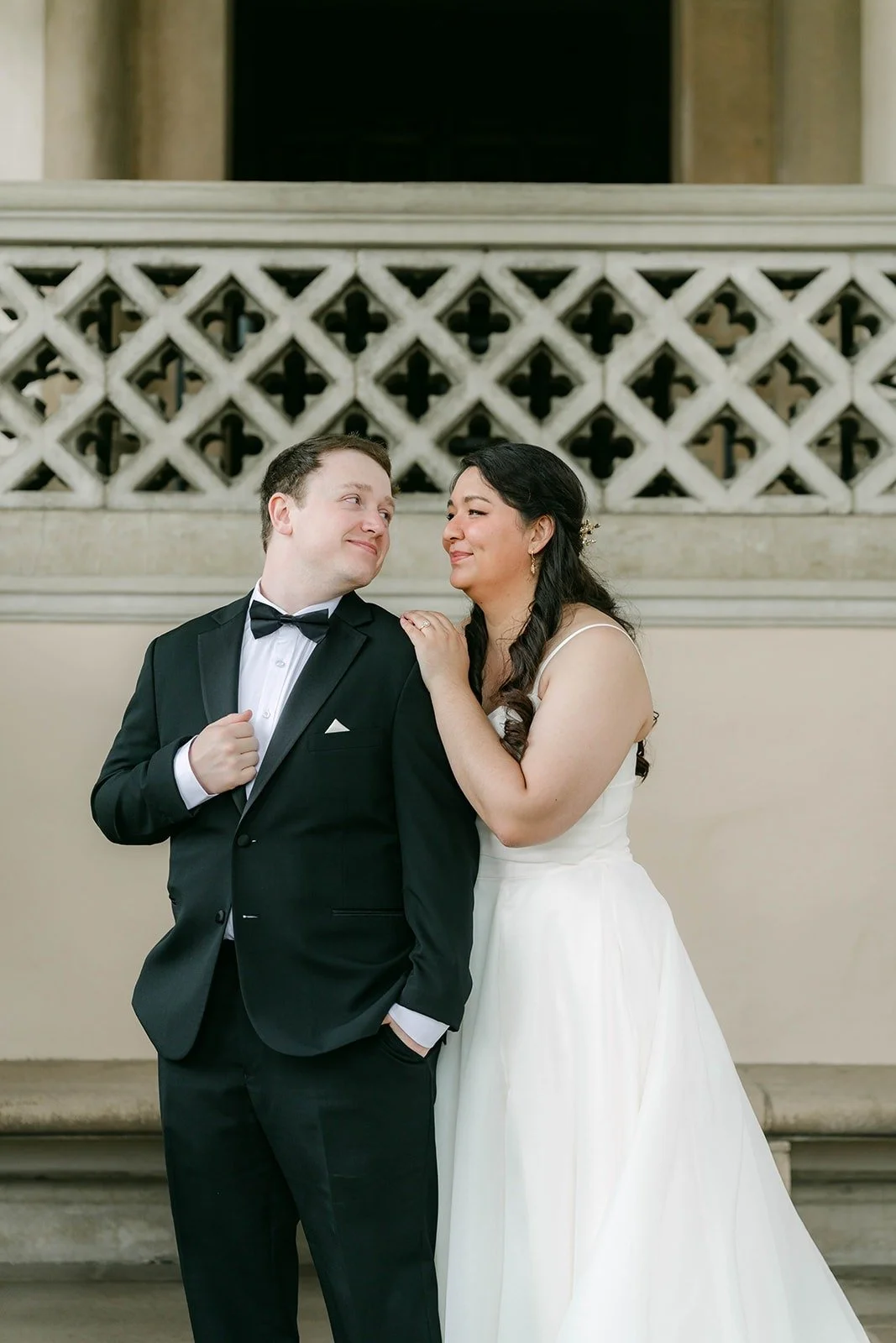 Saira and Matthew laughing together in front of the lattice wall