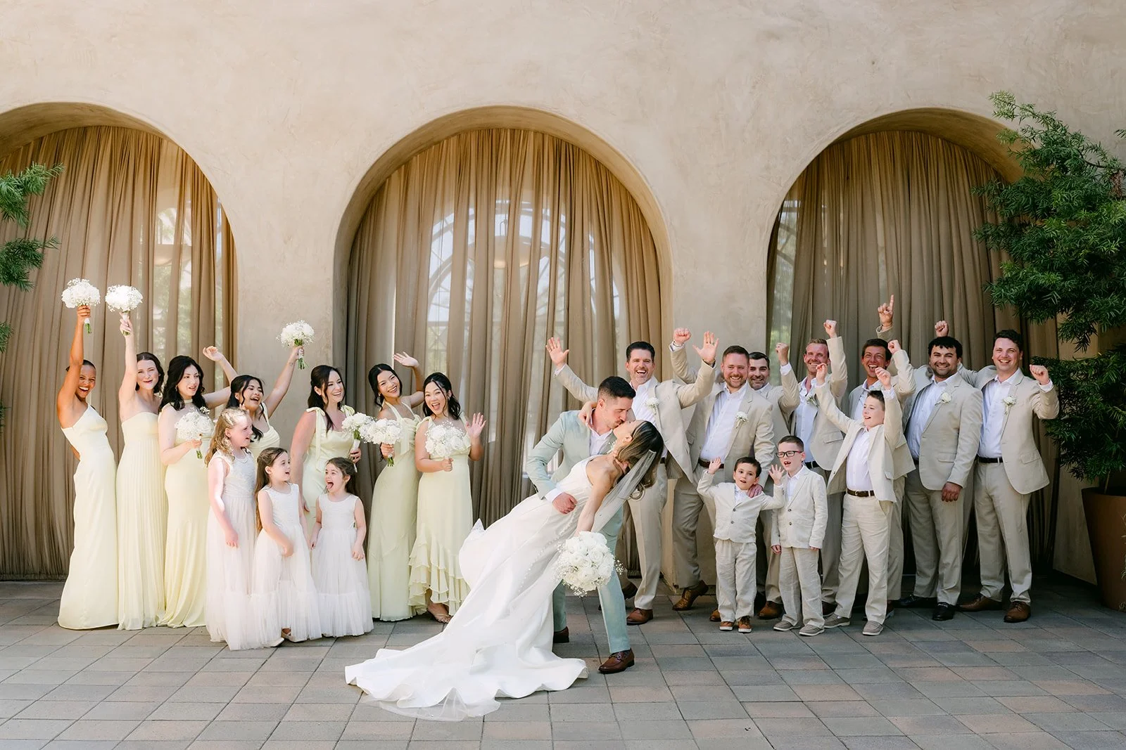 Wedding party cheering as the groom dips the bride