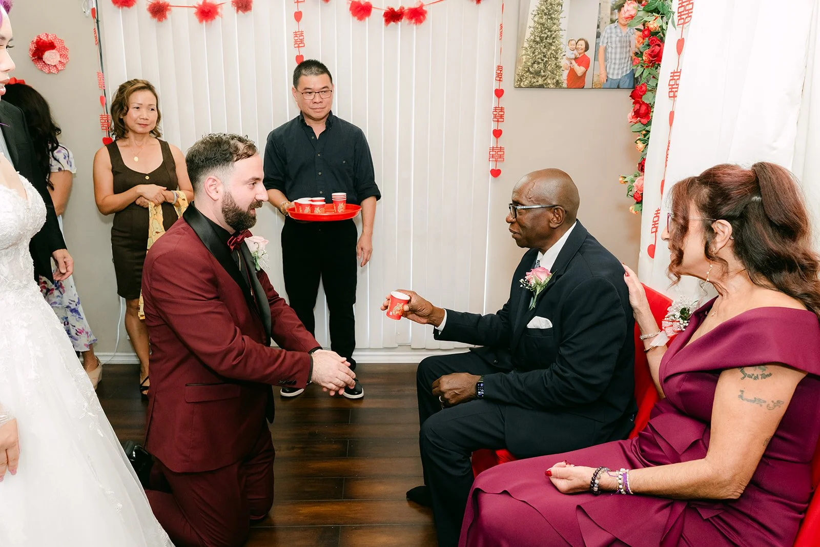 Ryan offering tea to family members, wide view of the room.
