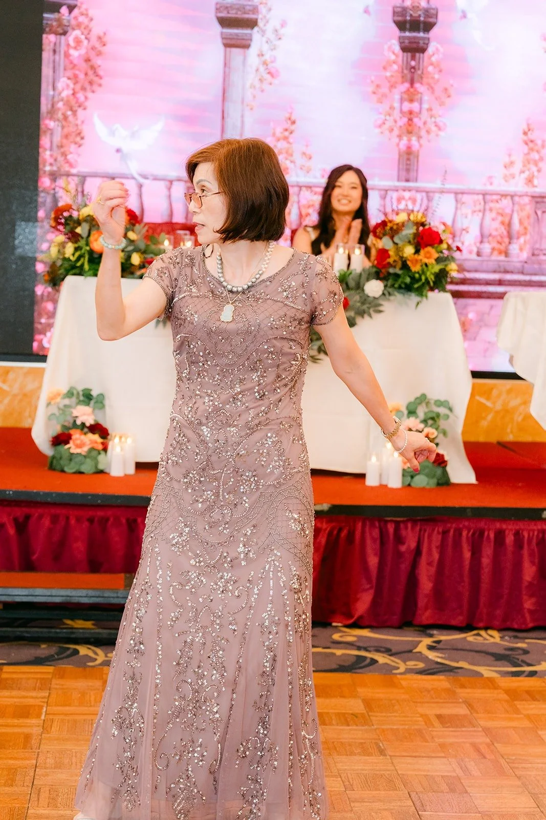A family member in a mauve gown dances during the parent dances