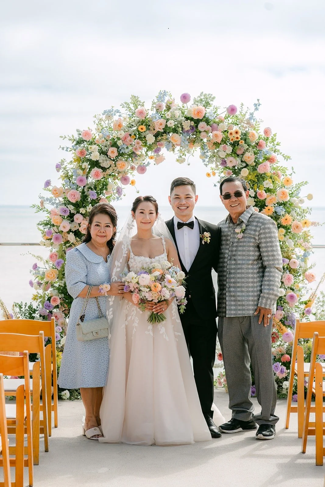 Kylie and Mario with two family members in front of the ceremony arch