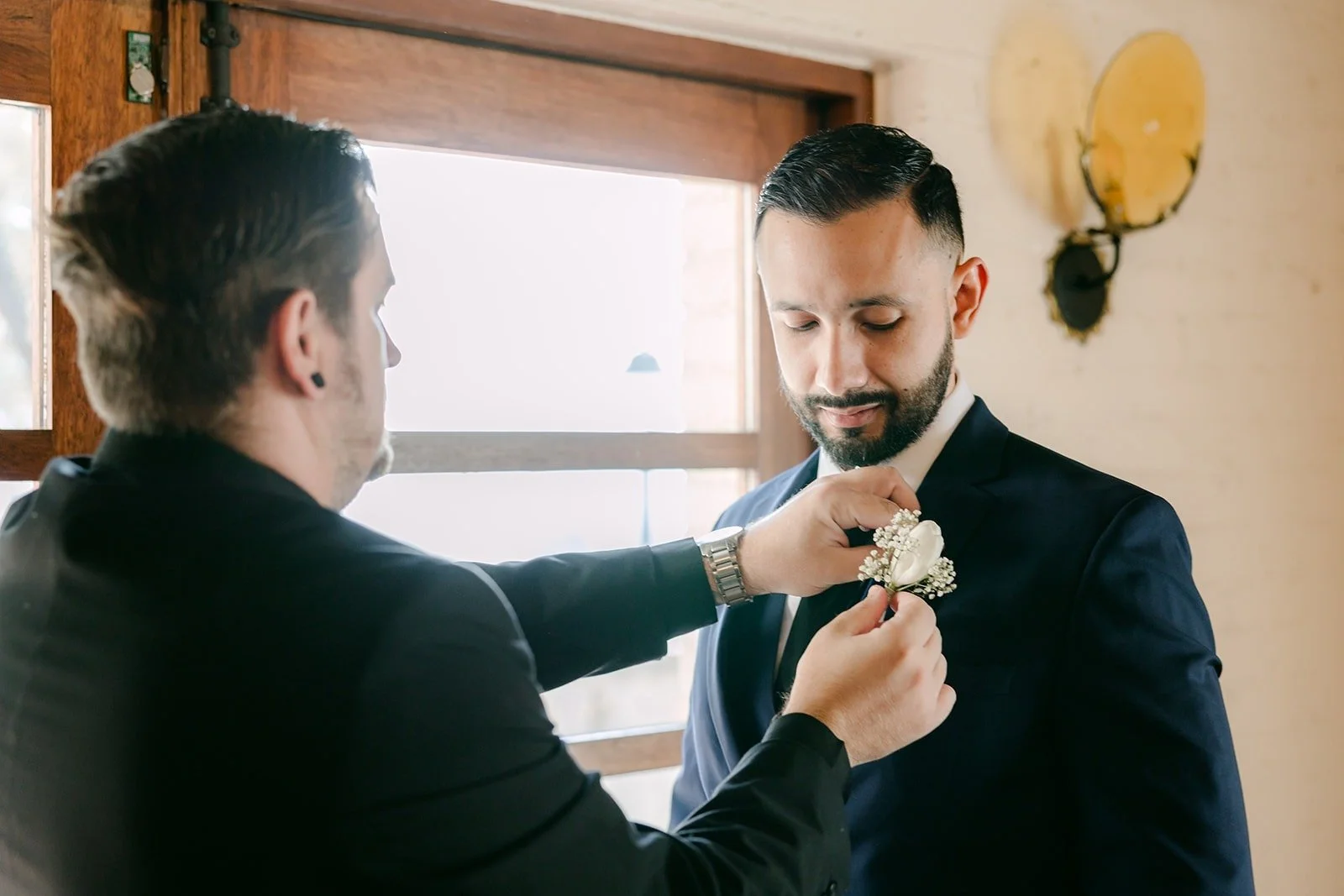 A friend pinning Danny's boutonniere by the window at Padua Hills Theatre