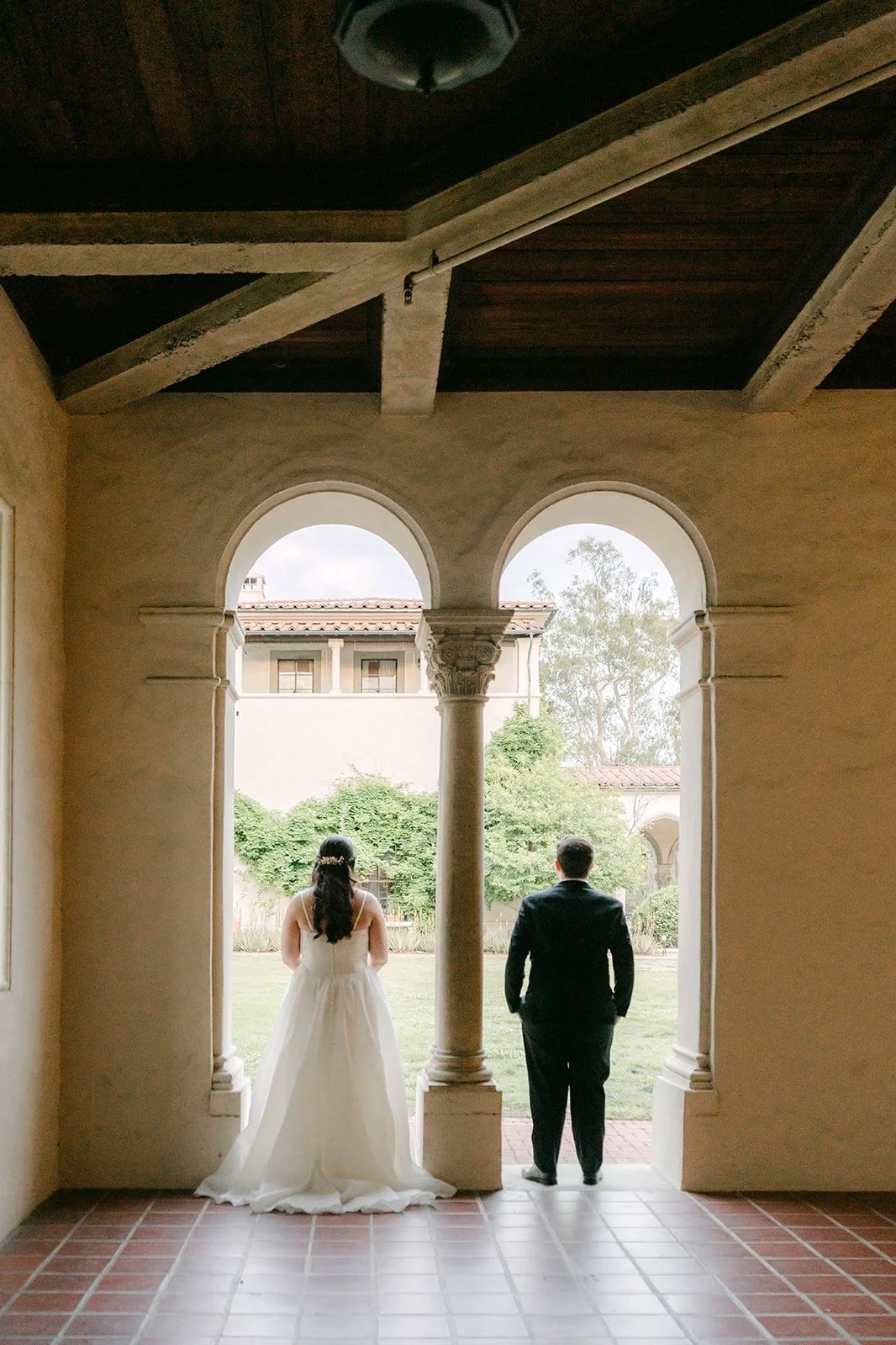 Saira and Matthew looking out through a pair of arched windows, photographed by One and Only Production