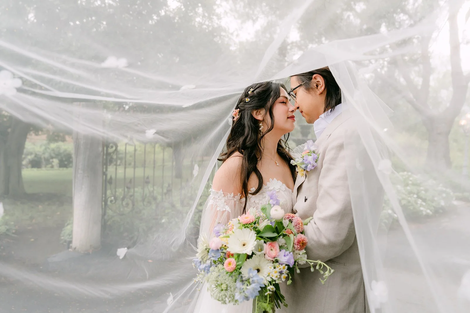 Kat and Mike close together under the veil in the garden