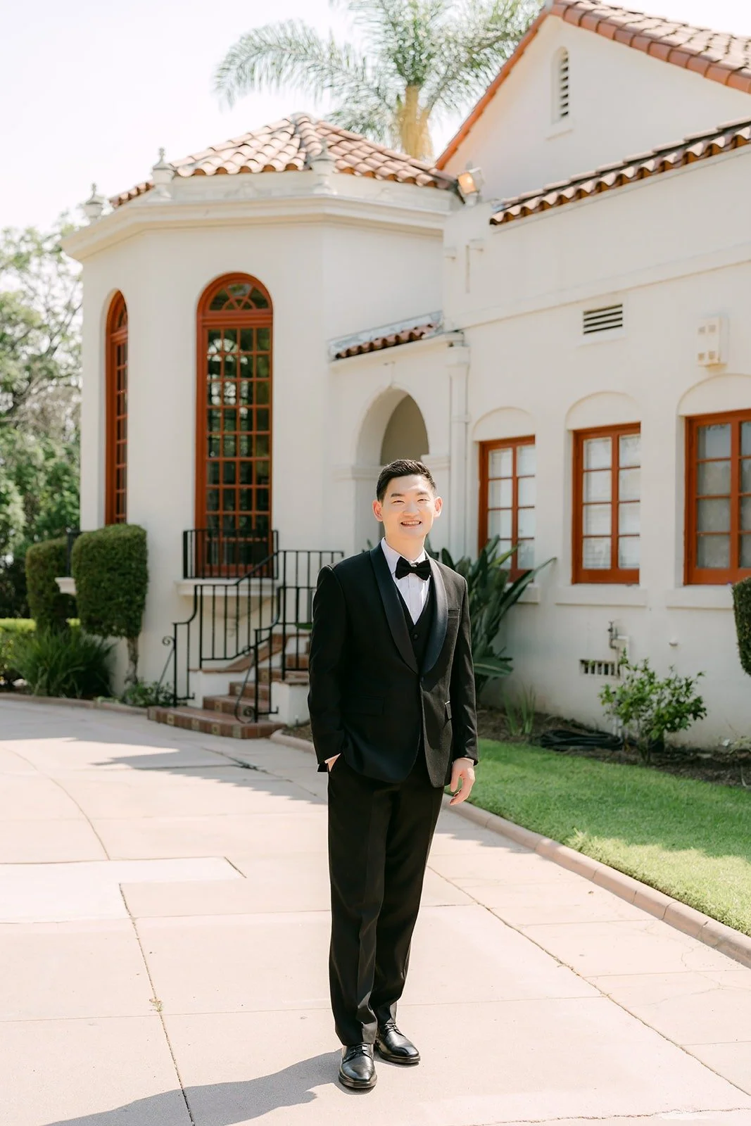 Sam in front of the white Spanish style mansion