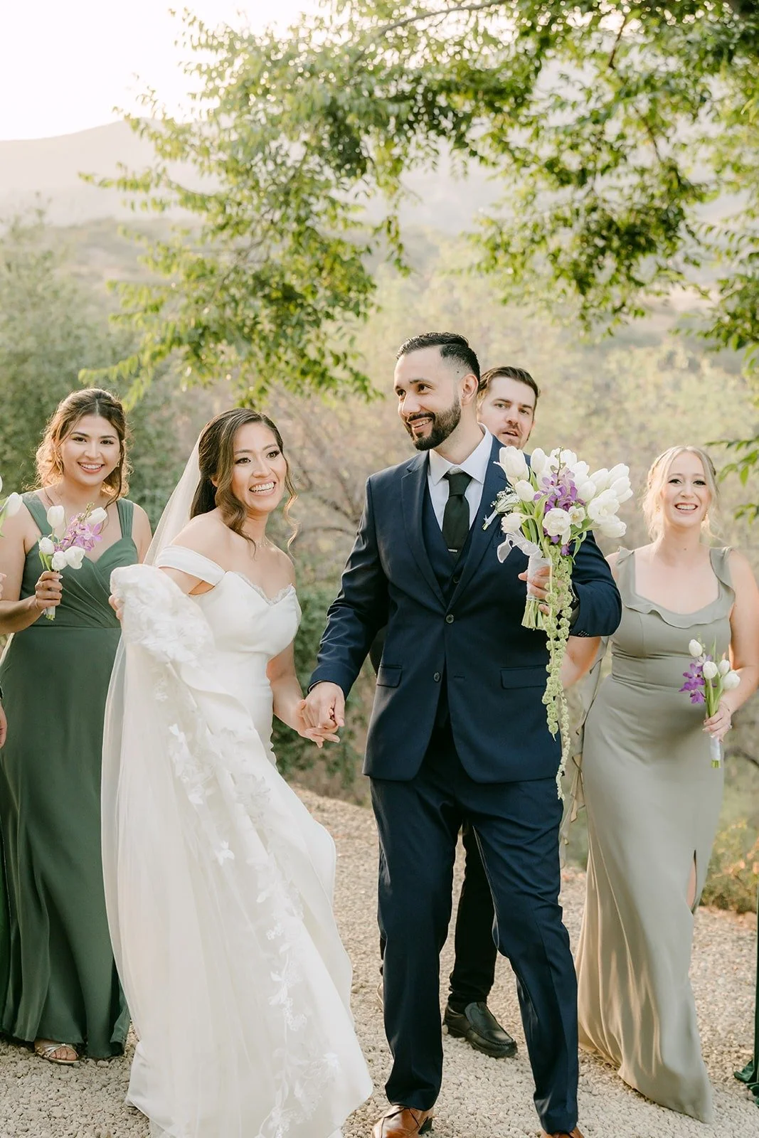 Mariana and Danny laughing with their wedding party in the golden light, photographed by One and Only Production