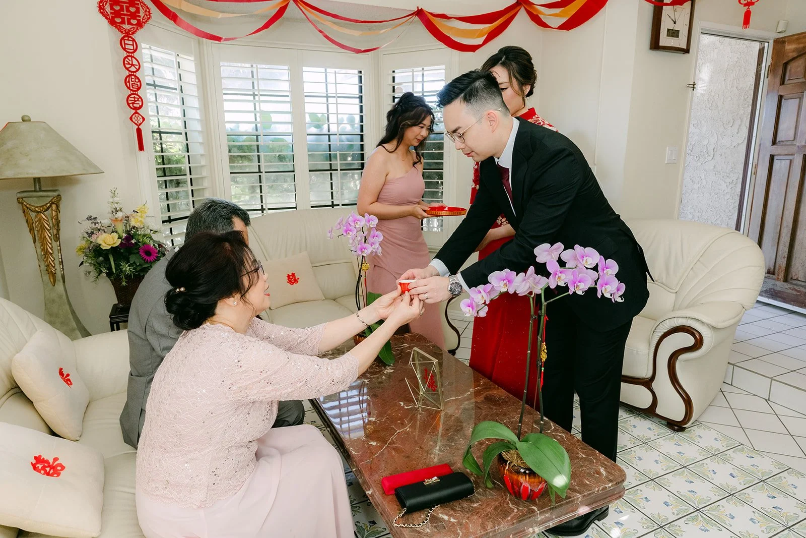 The couple serving tea to relatives on the sofa.